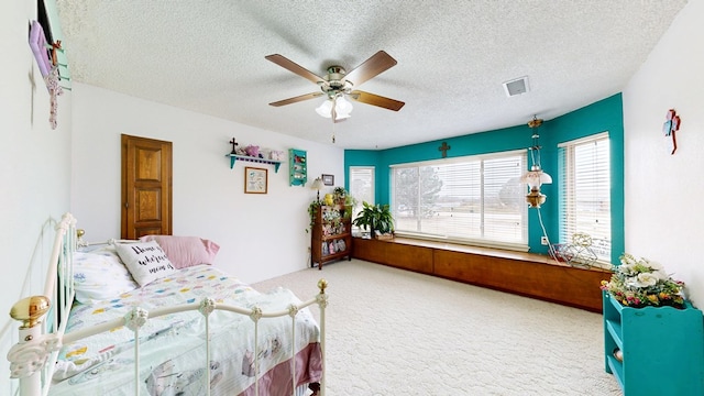 carpeted bedroom featuring a ceiling fan, visible vents, and a textured ceiling