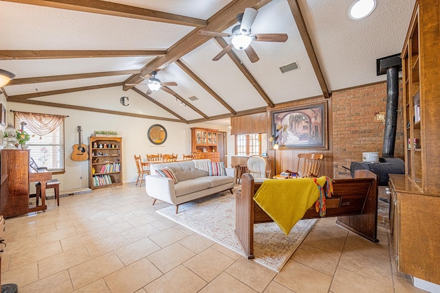 living room with a textured ceiling, ceiling fan, lofted ceiling with beams, visible vents, and a wood stove