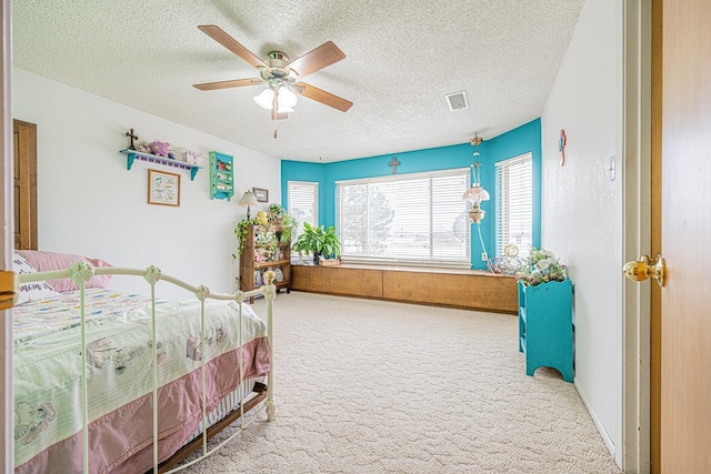 bedroom with a ceiling fan, carpet, visible vents, and a textured ceiling