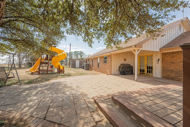 view of jungle gym featuring central air condition unit, an outdoor structure, french doors, a storage unit, and a patio area