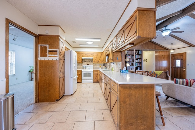 kitchen featuring a peninsula, white appliances, a sink, open floor plan, and light countertops