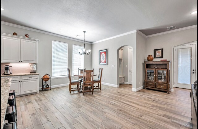 313 Peregrine Hill Cir, Midland, TX 79707 - dining room featuring visible vents, baseboards, arched walkways, light wood-type flooring, and crown molding