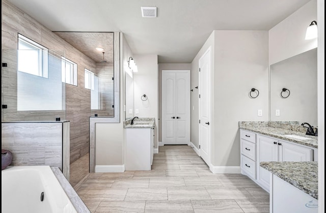 313 Peregrine Hill Cir, Midland, TX 79707 - bathroom with two vanities, a walk in shower, a bath, visible vents, and a sink