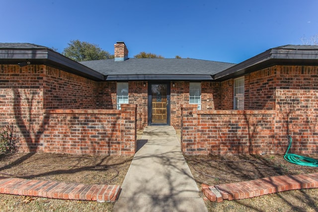 property entrance with brick siding and a chimney