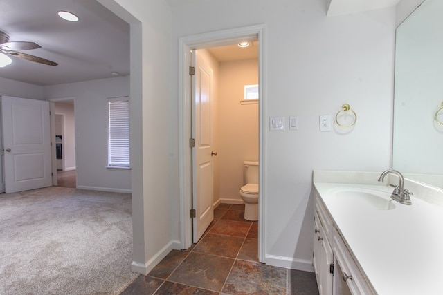 bathroom featuring vanity, toilet, baseboards, and ceiling fan