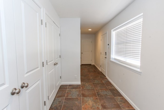 corridor with stone finish floor, recessed lighting, and baseboards