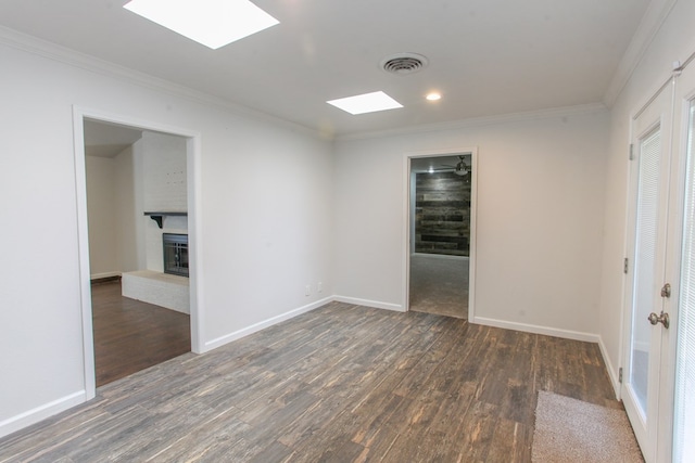 empty room with visible vents, ornamental molding, a fireplace, and wood finished floors