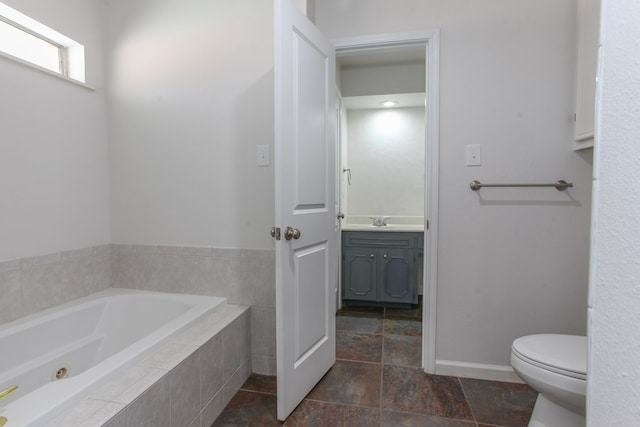 full bathroom with vanity, a garden tub, stone finish floor, and toilet