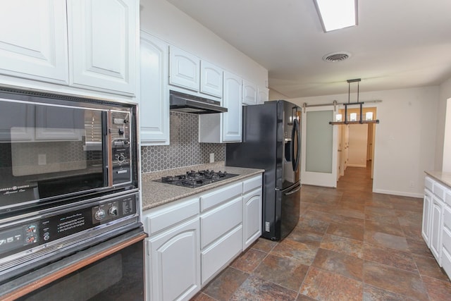 kitchen featuring visible vents, black fridge, under cabinet range hood, gas cooktop, and white cabinets