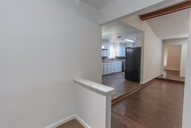 hall with beam ceiling, dark wood-type flooring, baseboards, and a sink