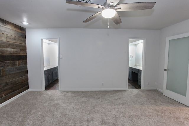 empty room with baseboards, carpet, wood walls, and a ceiling fan