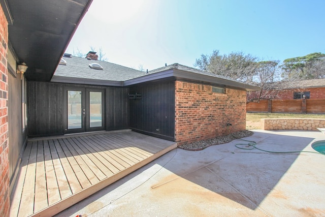 exterior space featuring a patio, fence, french doors, a deck, and brick siding