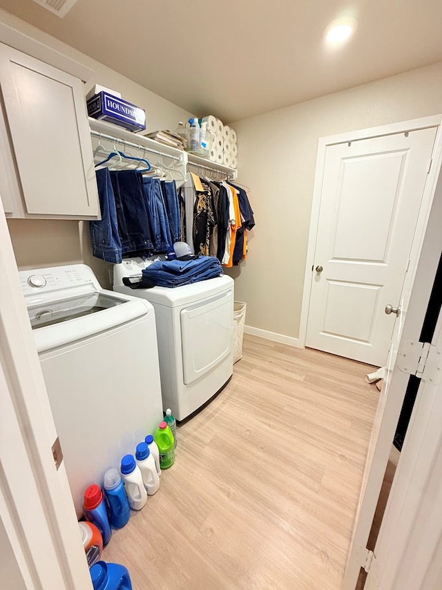 laundry area with cabinets, washing machine and clothes dryer, and light wood-type flooring