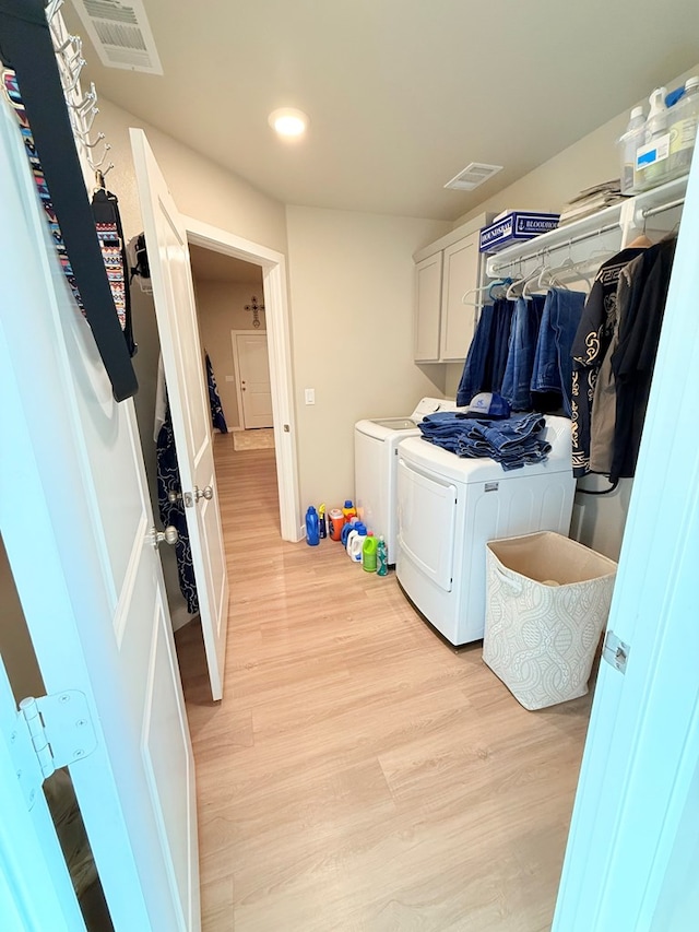 laundry area with cabinets, light hardwood / wood-style floors, and washer and dryer