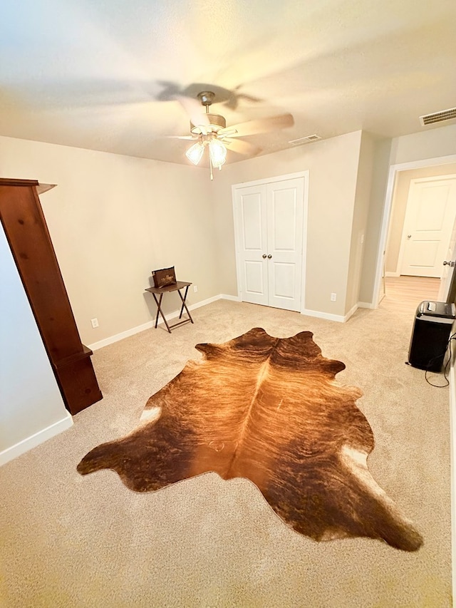 interior space featuring light colored carpet and ceiling fan