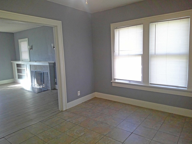 spare room featuring a fireplace and light tile patterned floors