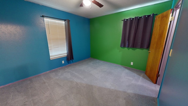 empty room with light carpet, ceiling fan, and a textured ceiling