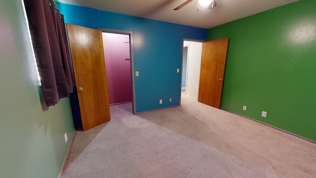 bedroom featuring light carpet, ceiling fan, and a textured ceiling