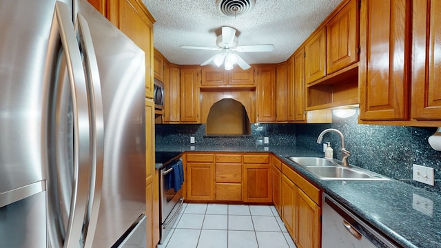 kitchen featuring appliances with stainless steel finishes, dark countertops, visible vents, and a sink