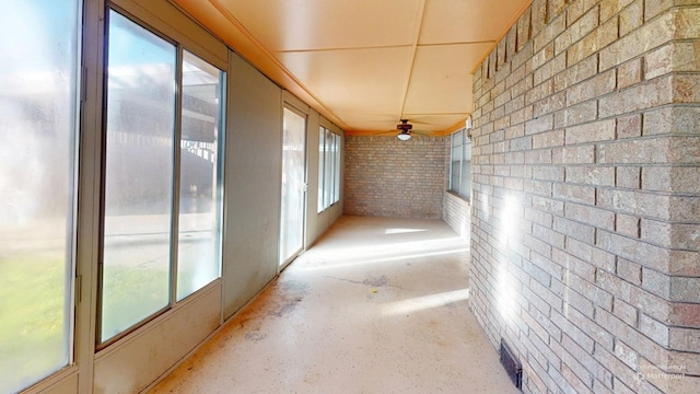 hall featuring brick wall and unfinished concrete floors