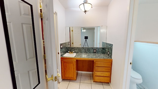 bathroom with toilet, tile patterned flooring, decorative backsplash, and vanity