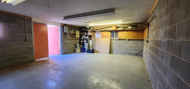 finished basement featuring concrete block wall, electric panel, and a textured ceiling