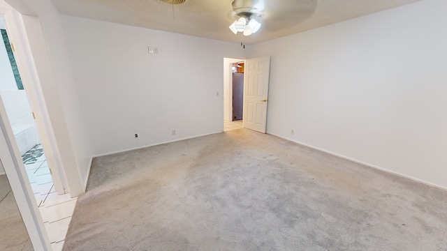 unfurnished room with light colored carpet, ceiling fan, a textured ceiling, and baseboards