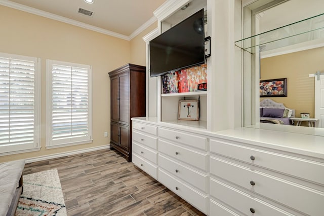 interior space with baseboards, ornamental molding, light wood-style flooring, and visible vents