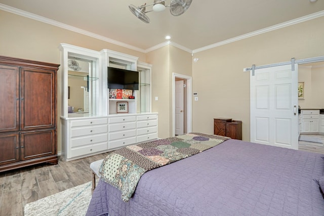 bedroom with crown molding, a barn door, and light wood-style flooring