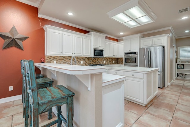 kitchen with ornamental molding, a peninsula, a kitchen bar, appliances with stainless steel finishes, and backsplash