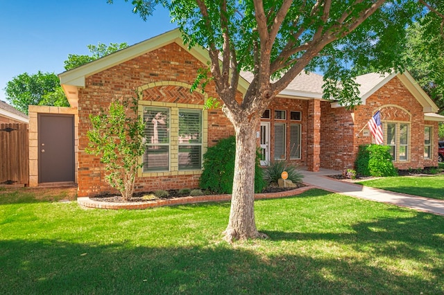 ranch-style home with brick siding, a front lawn, and fence