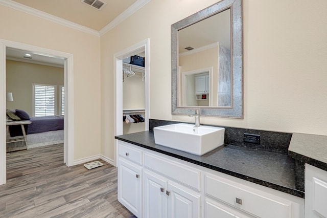 bathroom featuring visible vents, crown molding, wood finished floors, vanity, and baseboards