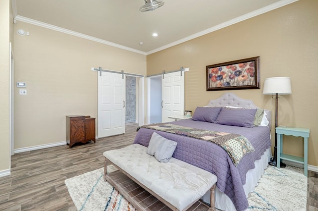 bedroom with crown molding, wood finished floors, baseboards, recessed lighting, and a barn door