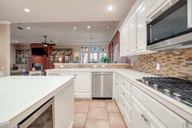 kitchen featuring a peninsula, beverage cooler, ceiling fan, a sink, and appliances with stainless steel finishes