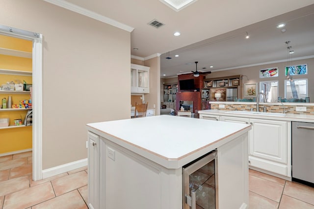 kitchen with visible vents, a ceiling fan, ornamental molding, beverage cooler, and a sink
