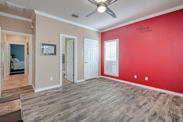 unfurnished bedroom featuring crown molding, baseboards, wood finished floors, and visible vents