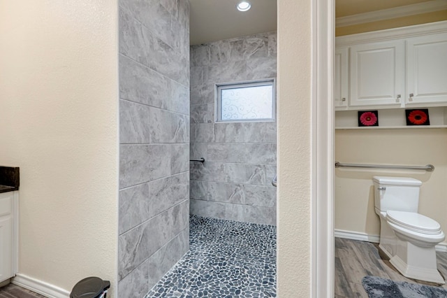 full bathroom with wood finished floors, toilet, ornamental molding, recessed lighting, and tiled shower