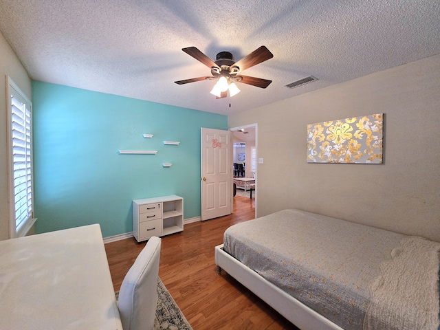 bedroom featuring ceiling fan, hardwood / wood-style floors, and a textured ceiling