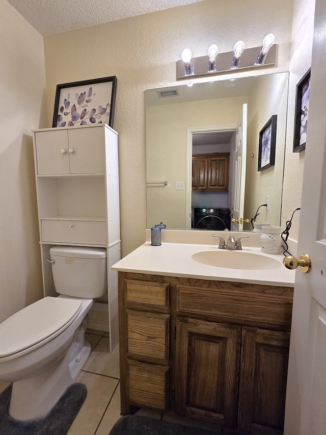 bathroom featuring washer / dryer, vanity, toilet, tile patterned floors, and a textured ceiling