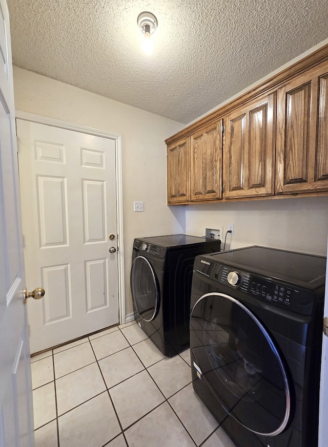 washroom with cabinets, washer and clothes dryer, a textured ceiling, and light tile patterned floors