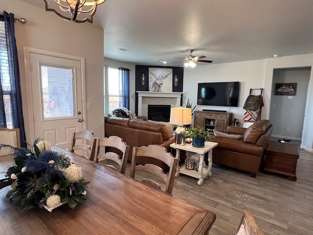 8409 E County Rd 113, Midland, TX 79706 - dining room with light wood finished floors, a fireplace, a chandelier, a ceiling fan, and baseboards
