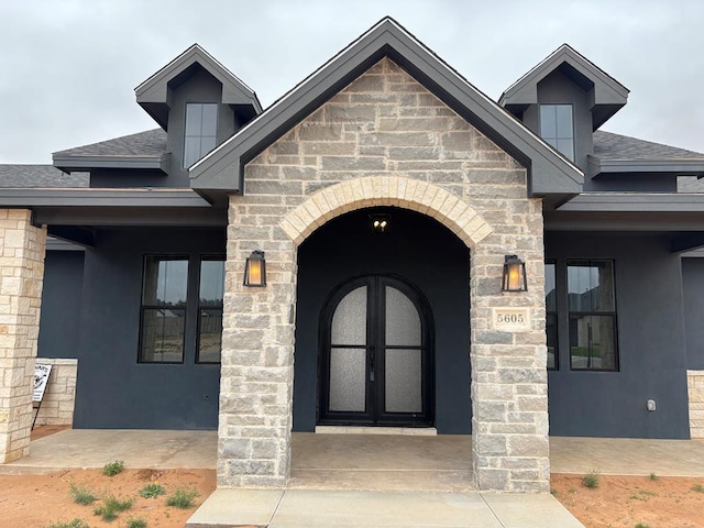 5605 E County Rd 94, Midland, TX 79706 - view of exterior entry featuring roof with shingles, stucco siding, and stone siding
