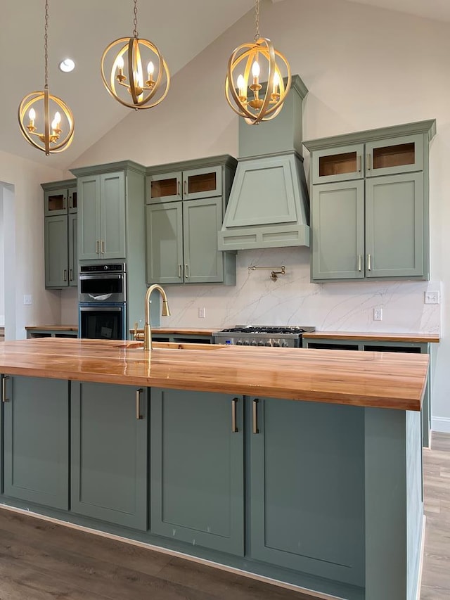5605 E County Rd 94, Midland, TX 79706 - kitchen with butcher block counters, a chandelier, green cabinets, vaulted ceiling, and stainless steel appliances