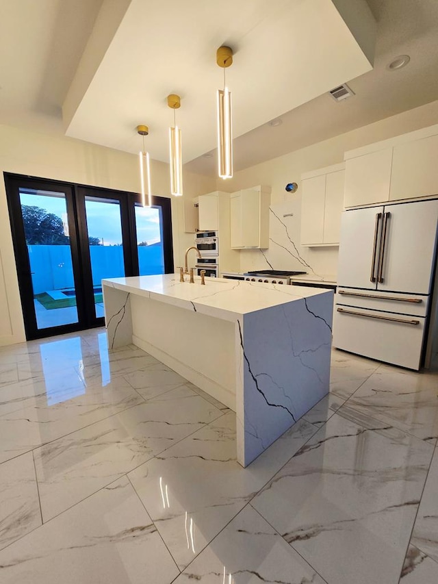 2607 Hoya Dr, Midland, TX 79707 - kitchen featuring high end fridge, modern cabinets, white cabinets, hanging light fixtures, and a kitchen island with sink