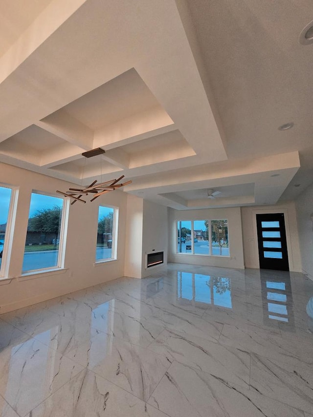 2607 Hoya Dr, Midland, TX 79707 - unfurnished living room featuring a glass covered fireplace, ceiling fan, coffered ceiling, plenty of natural light, and marble finish floors