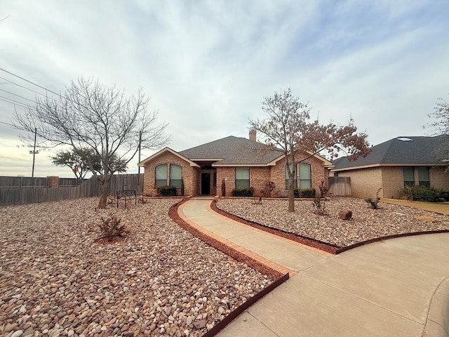 ranch-style home featuring brick siding, a chimney, and fence