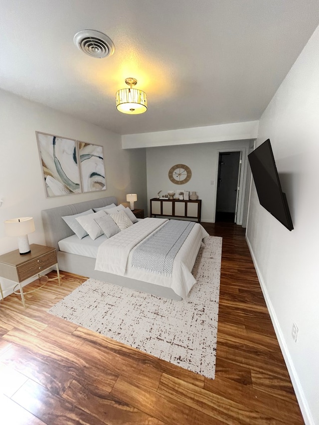 bedroom with wood finished floors, visible vents, and baseboards