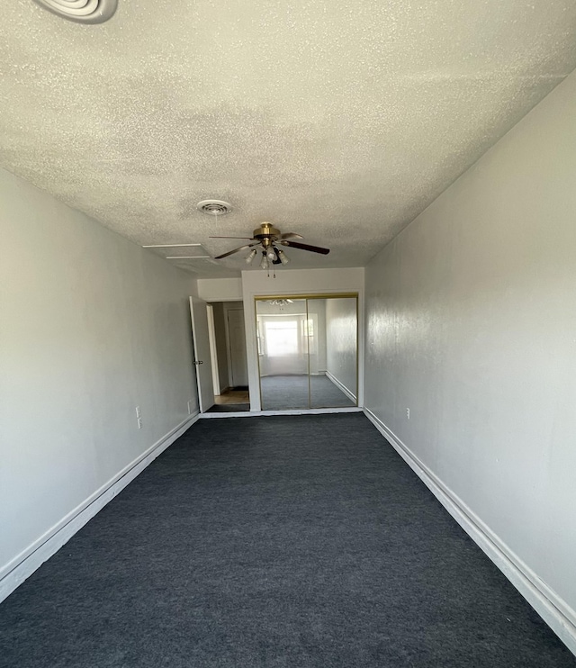 unfurnished room featuring ceiling fan, dark carpet, visible vents, and baseboards