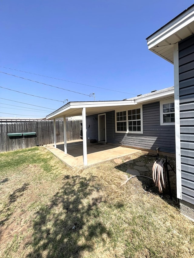 rear view of house featuring a lawn, a patio area, and fence