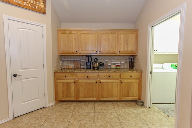 bar with washer and clothes dryer, light tile patterned floors, backsplash, and vaulted ceiling